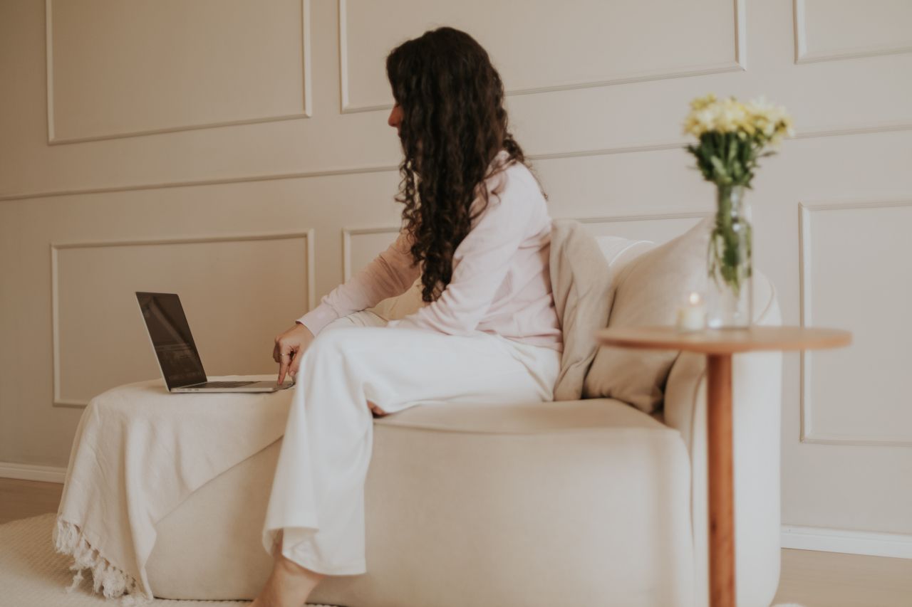 services-02 Woman working on a laptop in a minimalist home office with soft neutral tones and a peaceful ambiance.