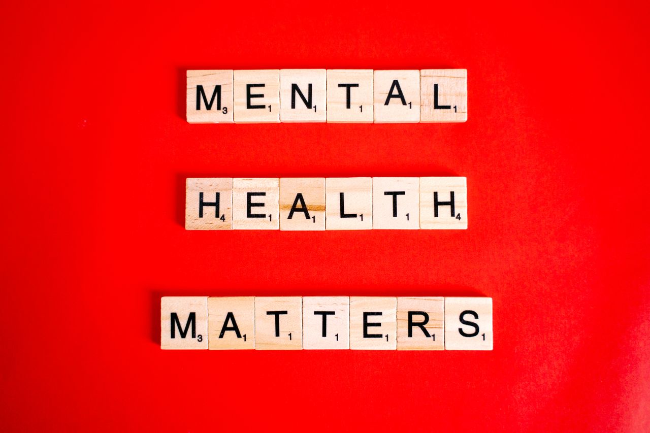services-01 Wooden tiles spelling 'Mental Health Matters' on a vivid red background.