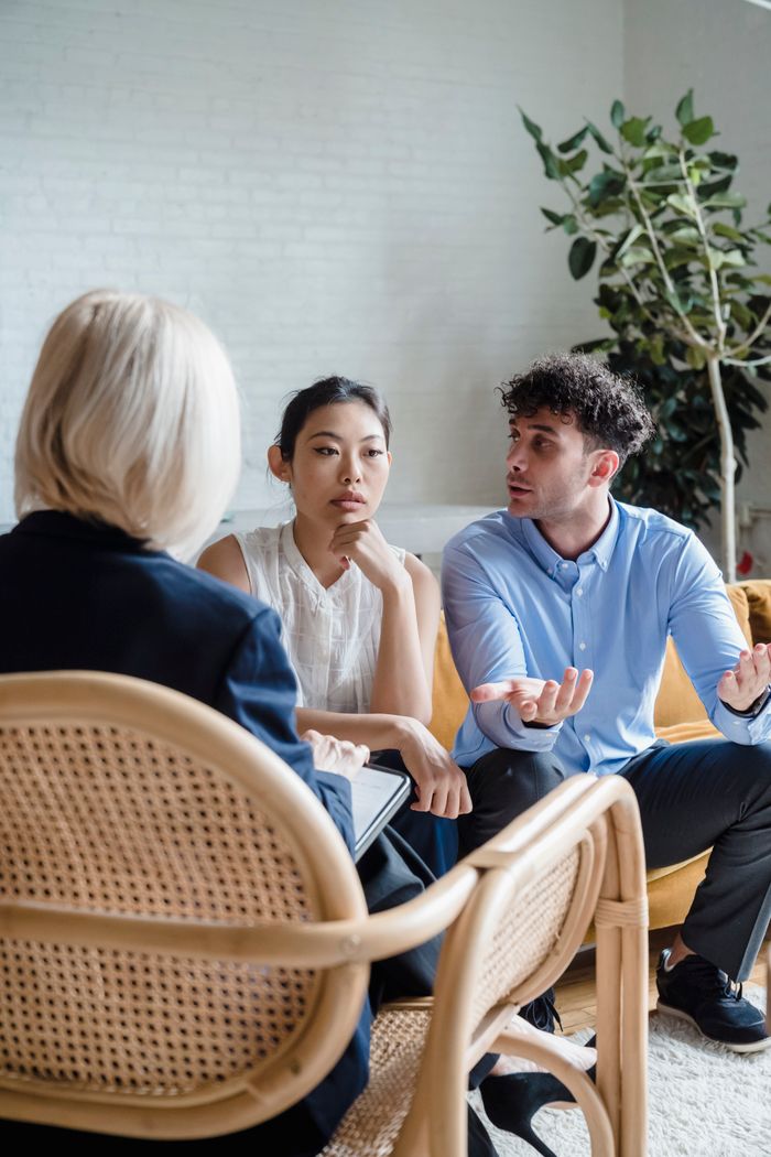 services-03 A couple discusses issues with a therapist in a modern office setting.