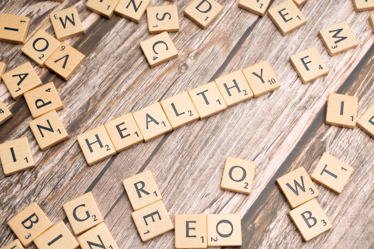 Wooden letter tiles arranged on a wooden surface spelling out 'healthy', symbolizing wellness.
